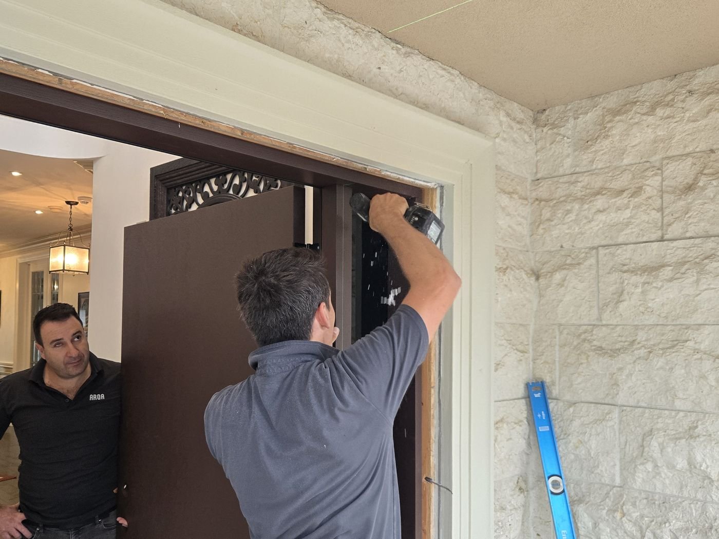 Installer fitting a front door into a frame with brick mould around the opening