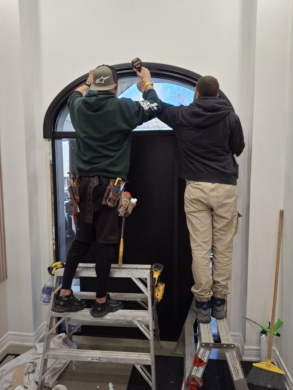 Two installers fitting an arched front door inside a home