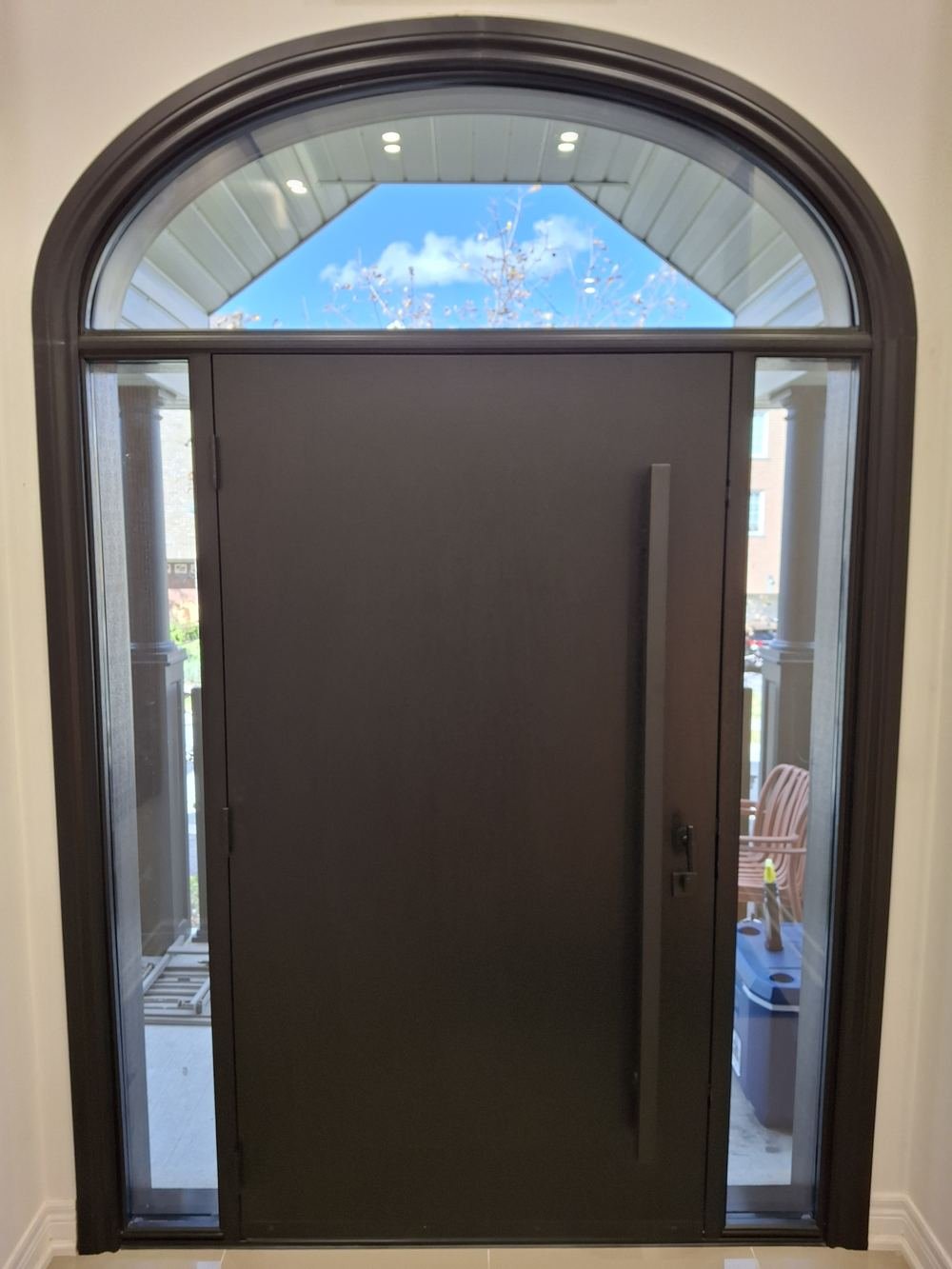 Interior view of a dark front door with arched transom and sidelites