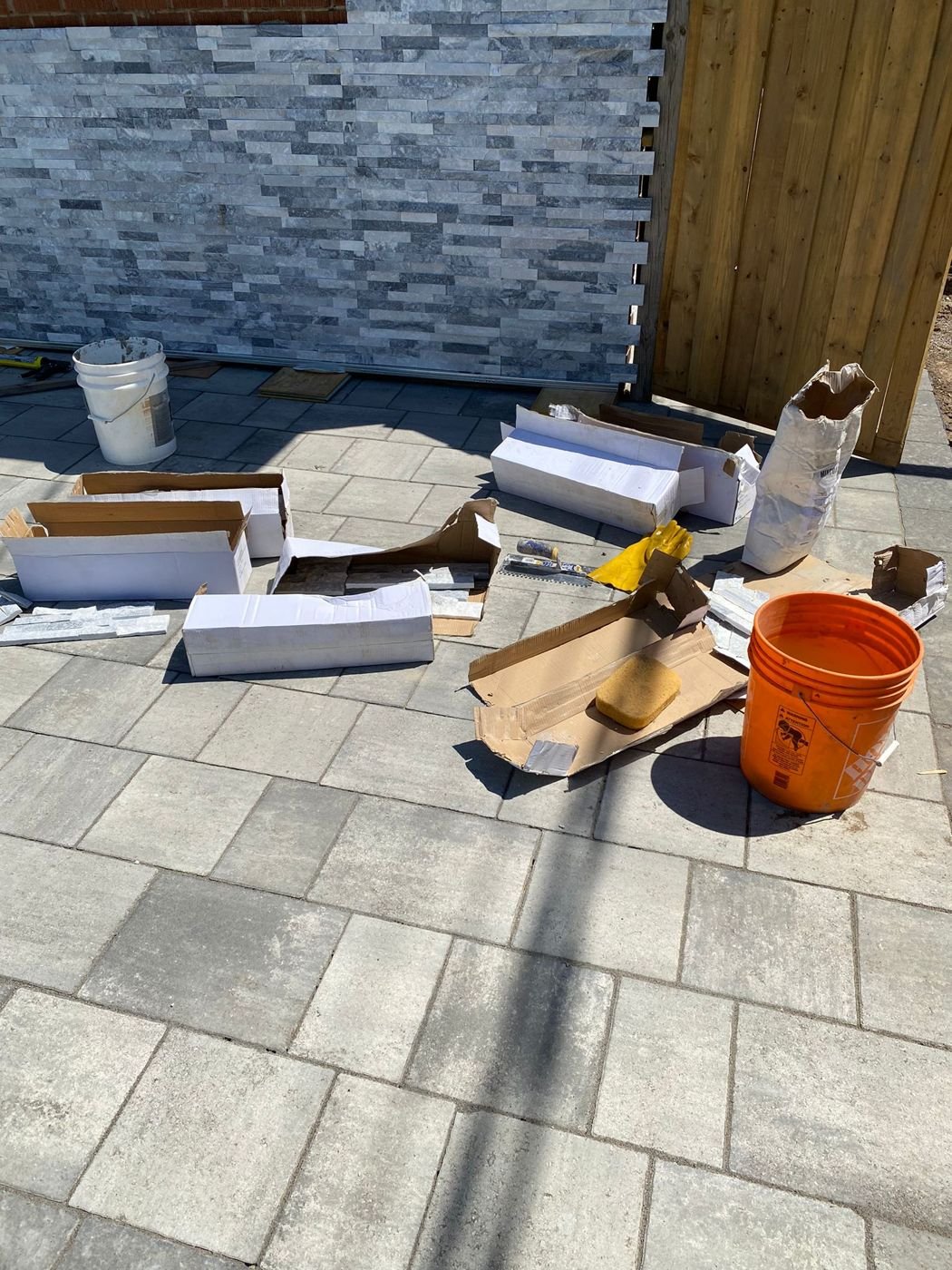 Interlocking pavers in front of a stone veneer wall being installed