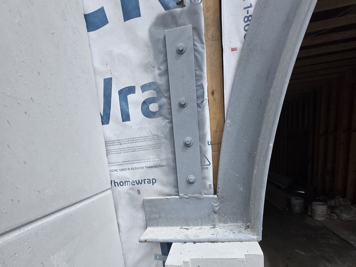 Close up of a bolted steel bracket and base plate where a curved lintel meets its support