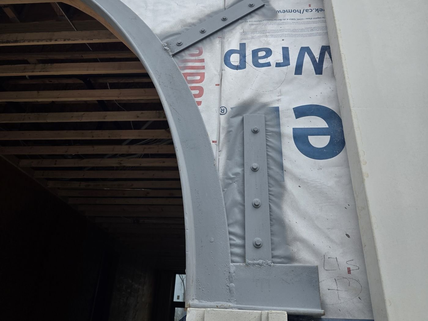Curved steel lintel set into an arched opening and fastened with steel brackets