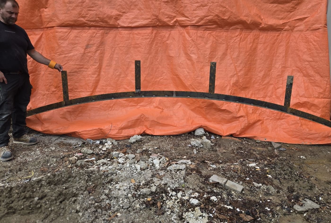 Curved steel lintel pieces with welded upright tabs laid out on site