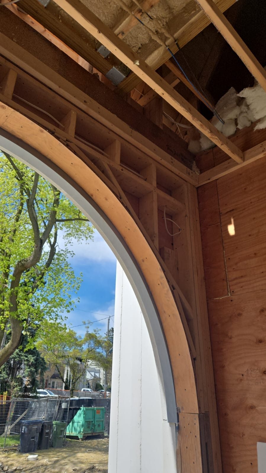 Curved steel lintel following an arched opening behind timber framing and precast