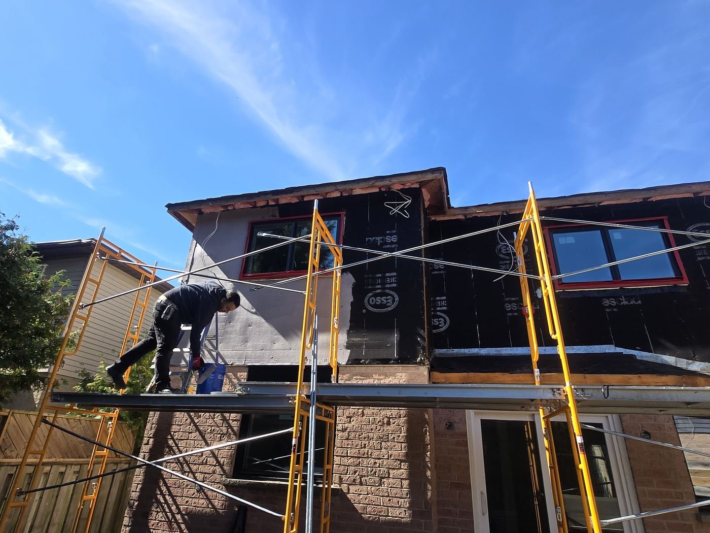 Crew member working on a scaffold at the rear of a home