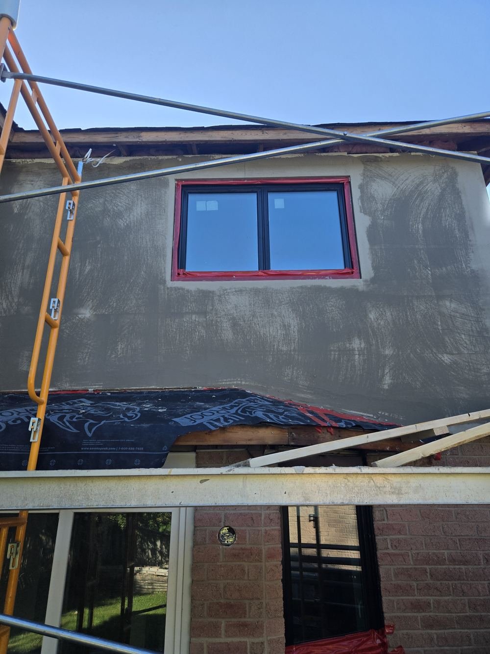 New window framed in stucco with scaffolding in front